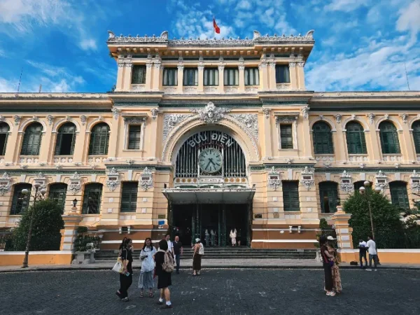 The ornate facade of Saigon Central Post Office beneath a blue sky